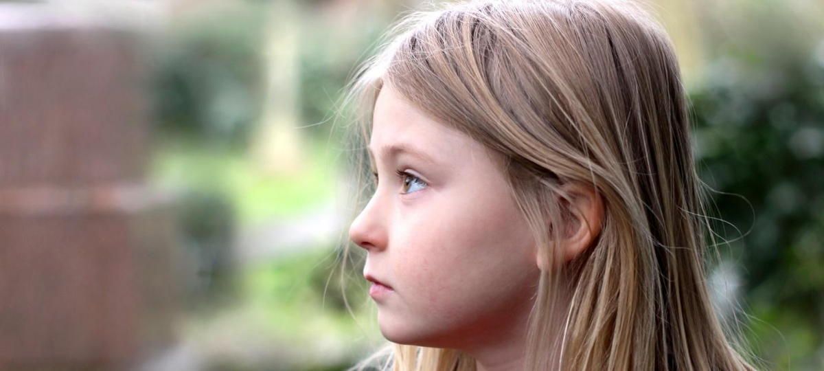 A young girl with long blonde hair is looking to the side. A young girl with long blonde hair is looking to the side.