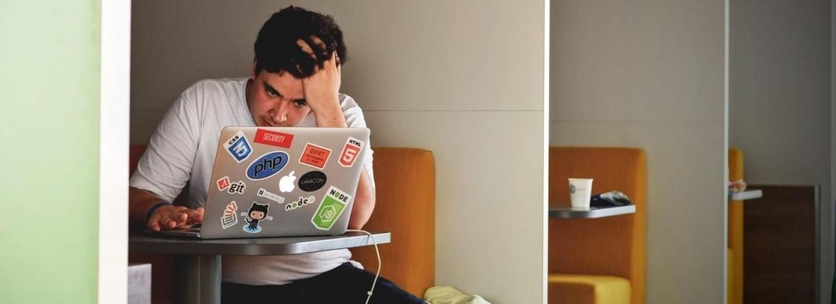 A man is sitting at a table using a laptop computer. A man is sitting at a table using a laptop computer.