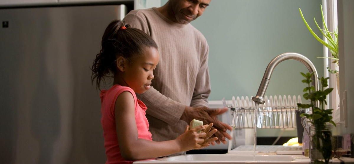 A man and a little girl are washing their hands in a kitchen sink. A man and a little girl are washing their hands in a kitchen sink.