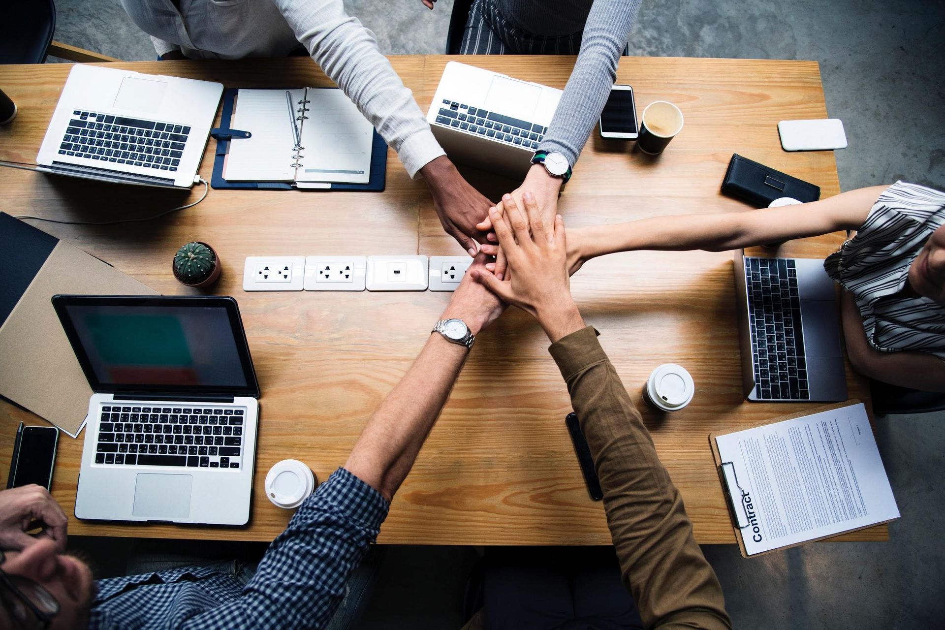 A group of people are putting their hands together at a table.