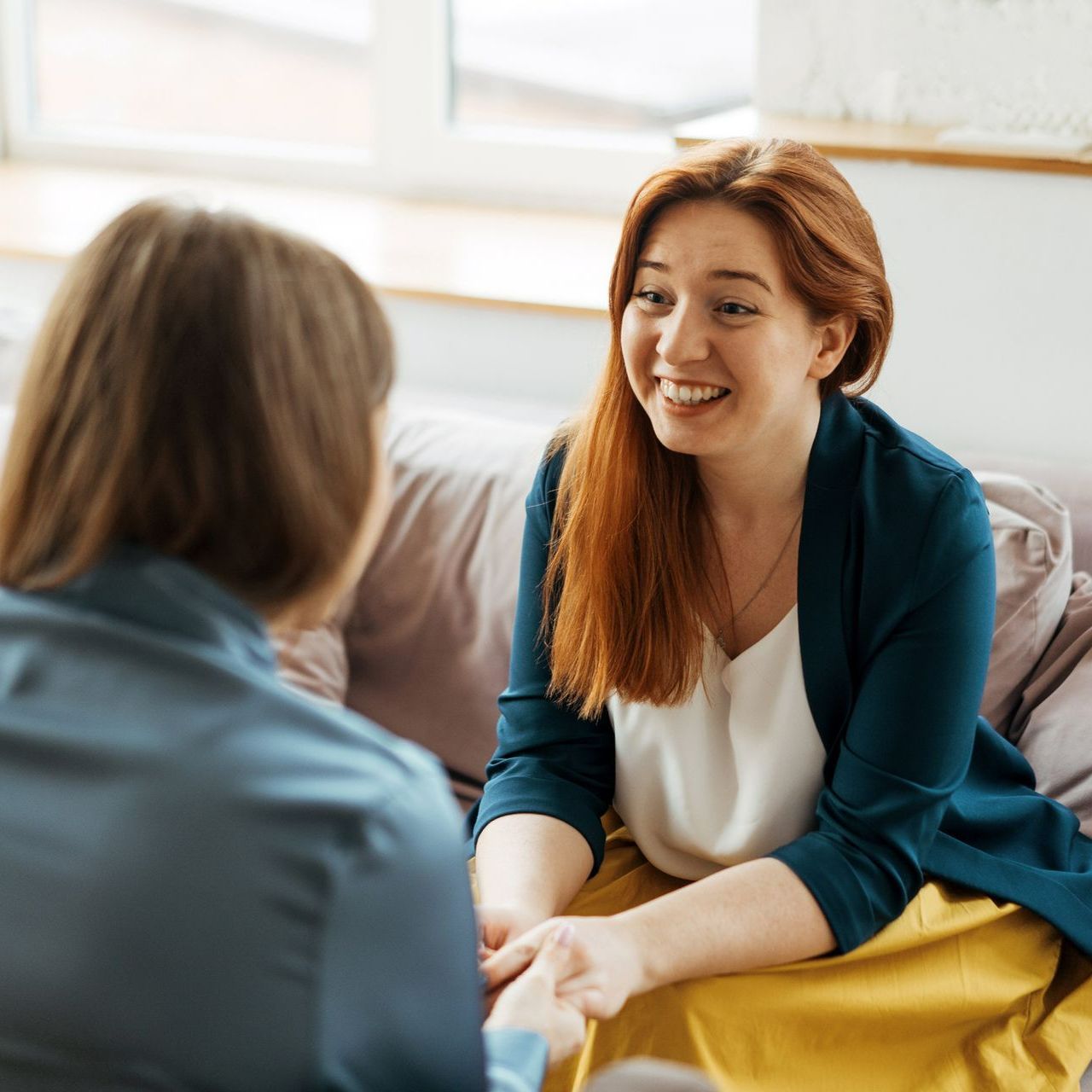 Two women are sitting on a couch talking to each other. Two women are sitting on a couch talking to each other.