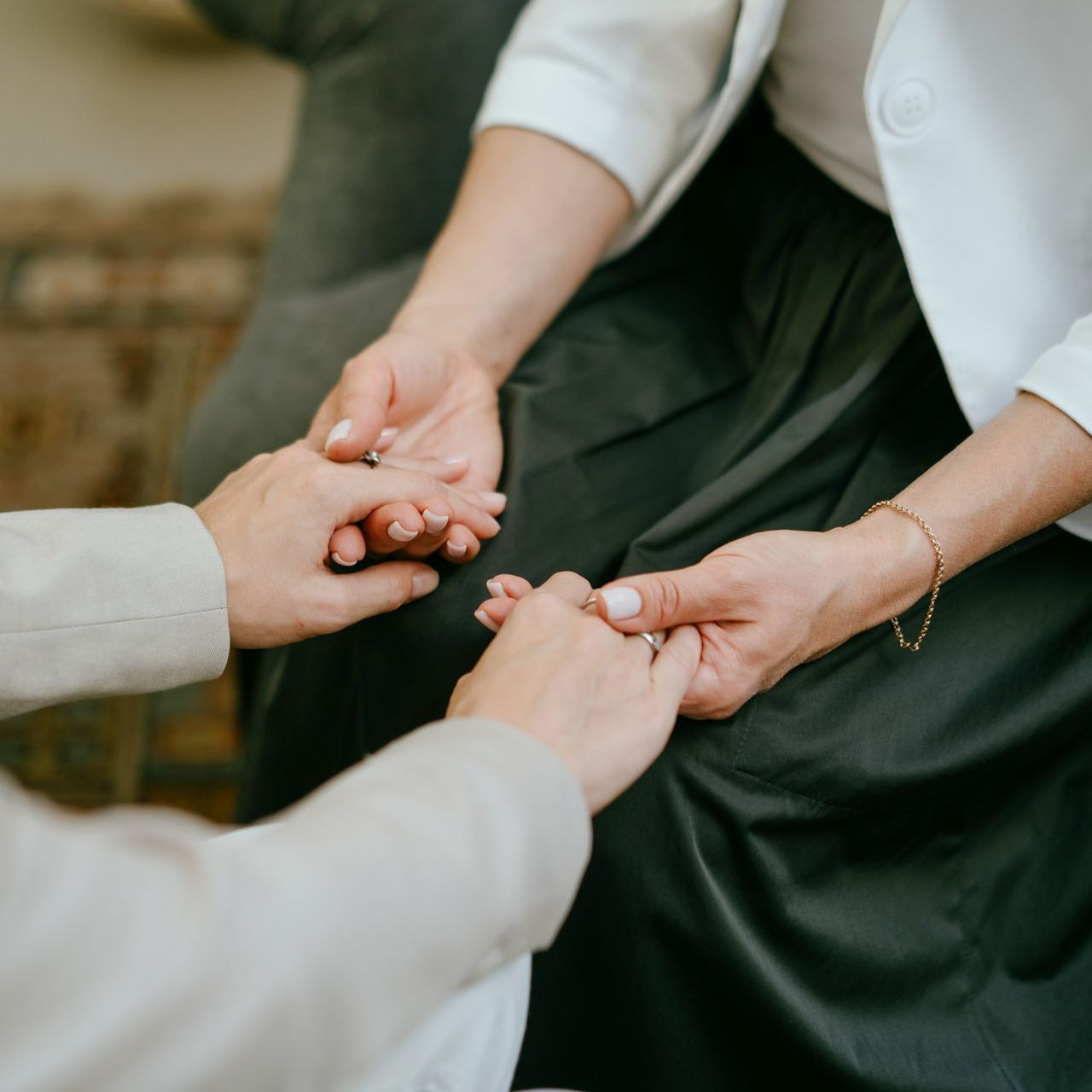 Two women are holding hands while sitting on a couch Two women are holding hands while sitting on a couch
