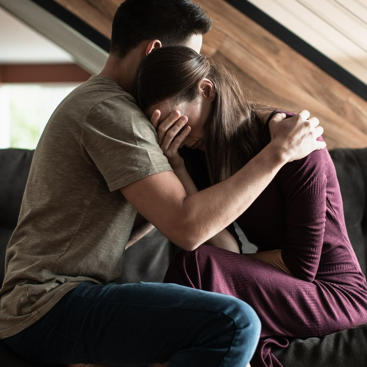 A man is comforting a woman who is sitting on a couch A man is comforting a woman who is sitting on a couch