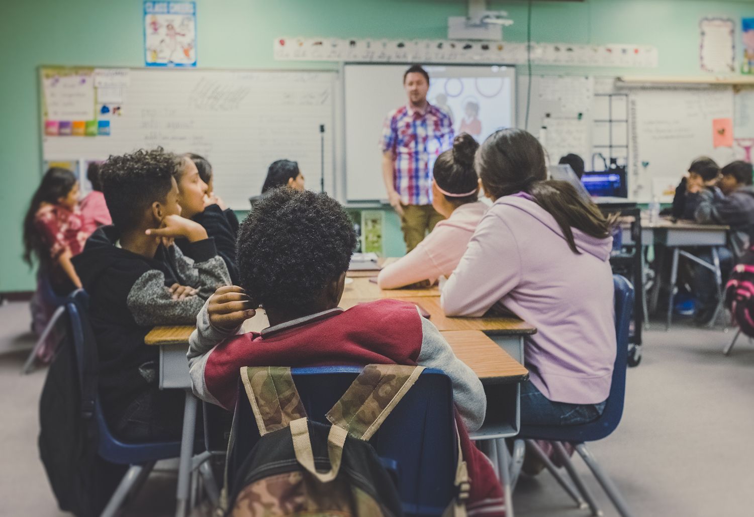 A teacher is giving a presentation to a group of students in a classroom.