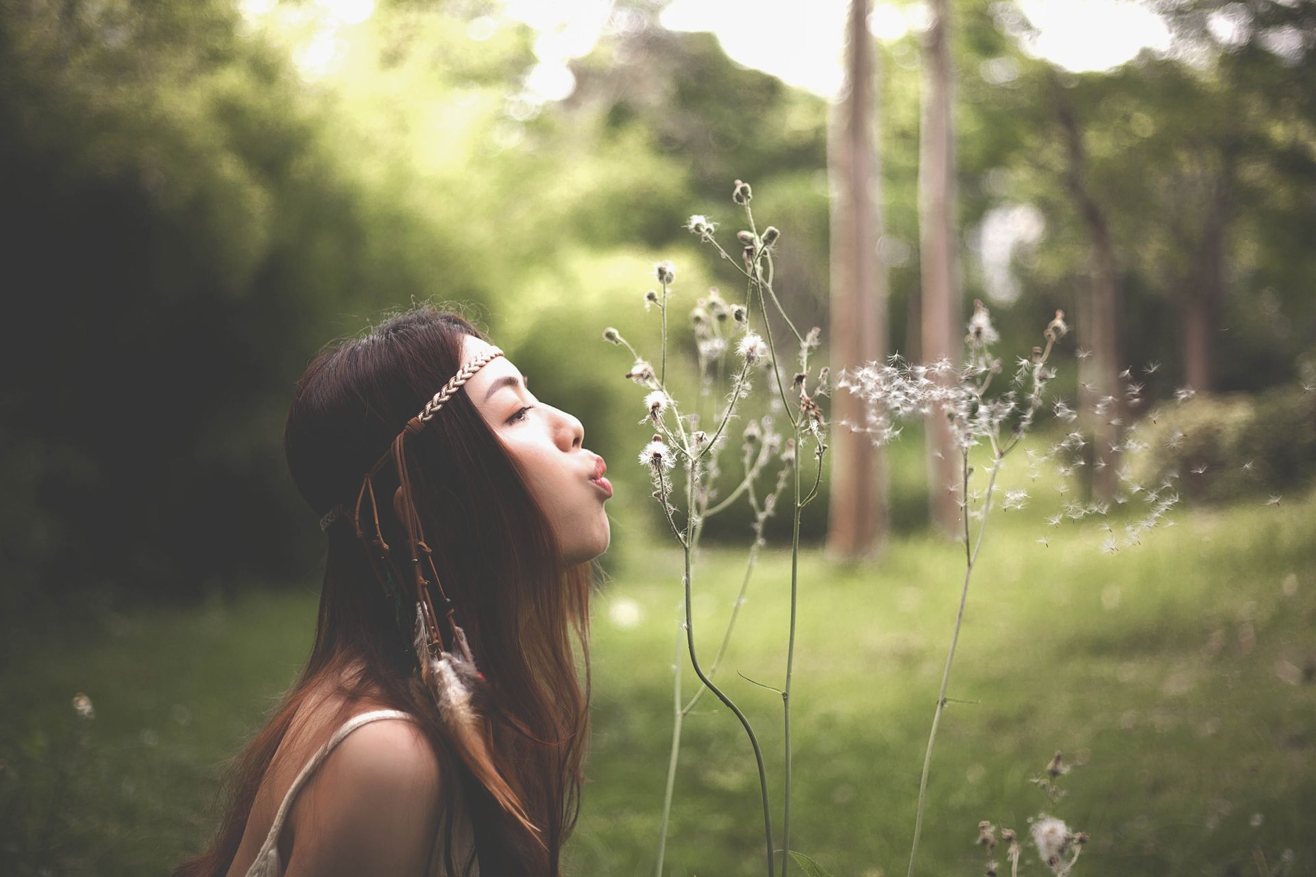 A woman is blowing dandelions in the air in a field. A woman is blowing dandelions in the air in a field.