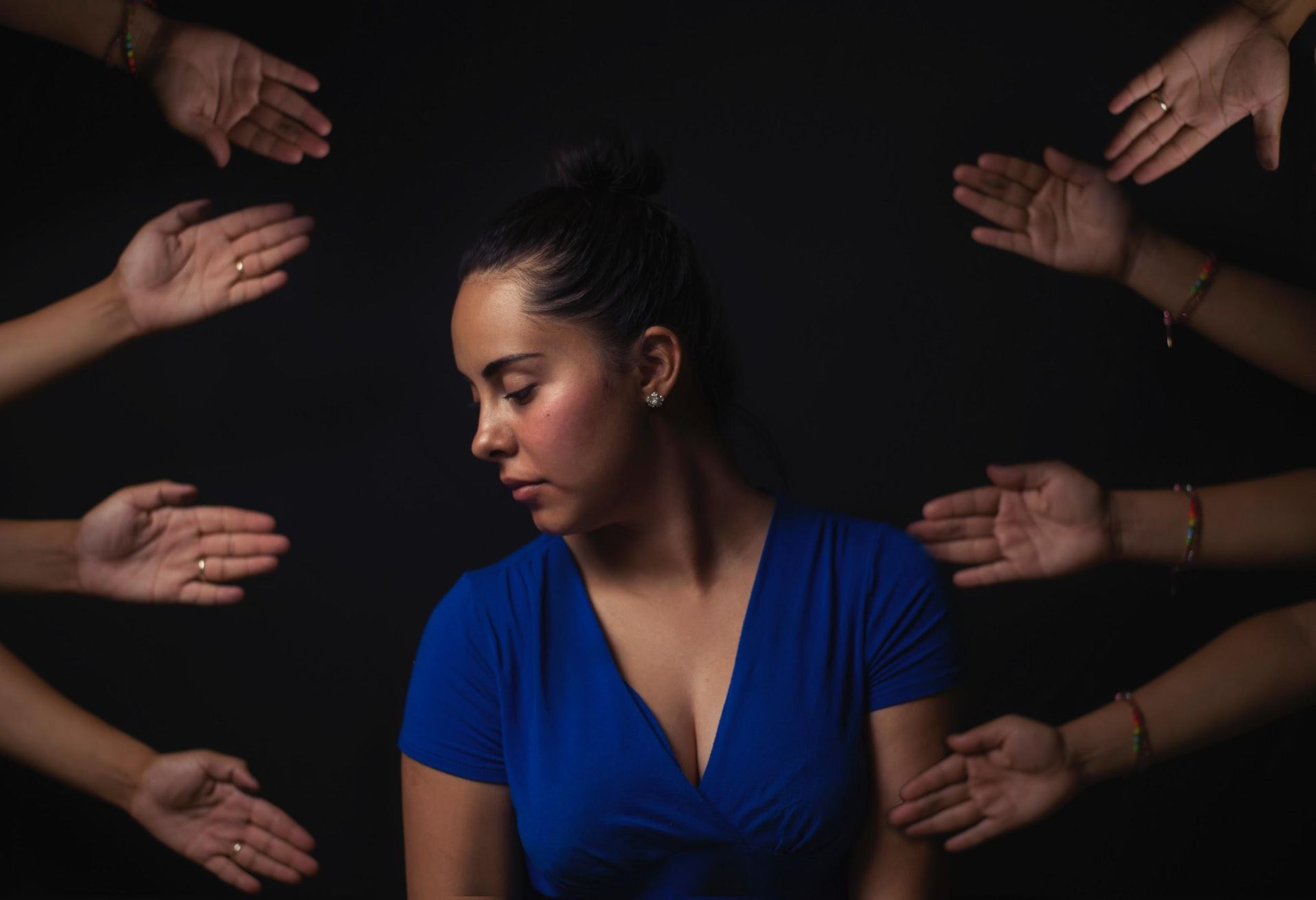 A woman in a blue dress is surrounded by many hands. A woman in a blue dress is surrounded by many hands.