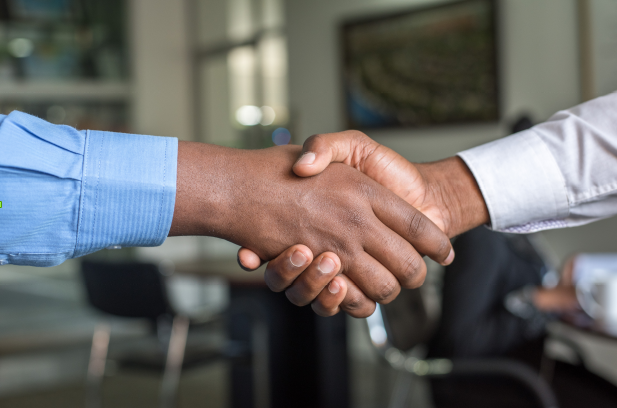 A close up of two men shaking hands in an office. A close up of two men shaking hands in an office.