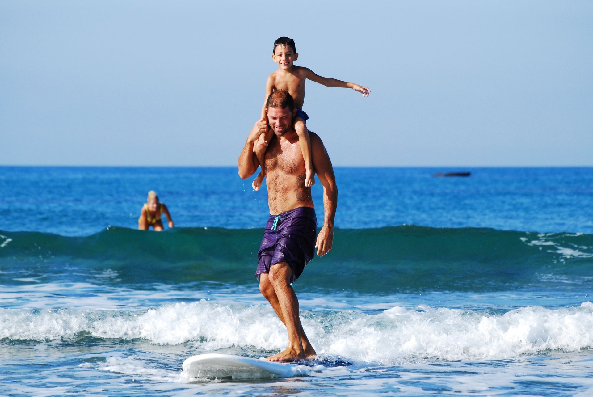 A man is carrying a child on his shoulders while surfing A man is carrying a child on his shoulders while surfing