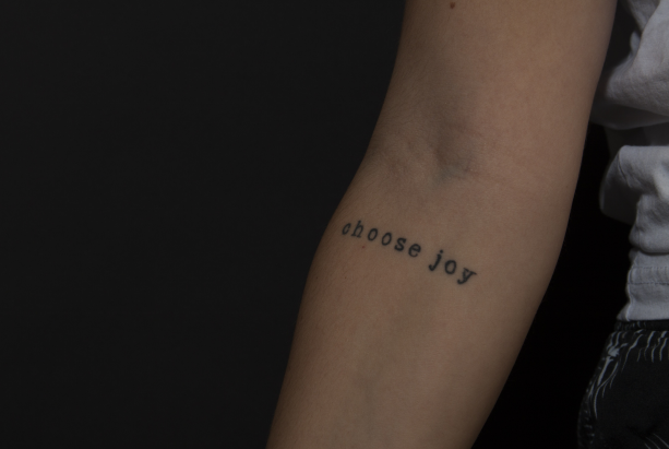 A woman has a tattoo on her arm that says `` choose joy ''. A woman has a tattoo on her arm that says `` choose joy ''.