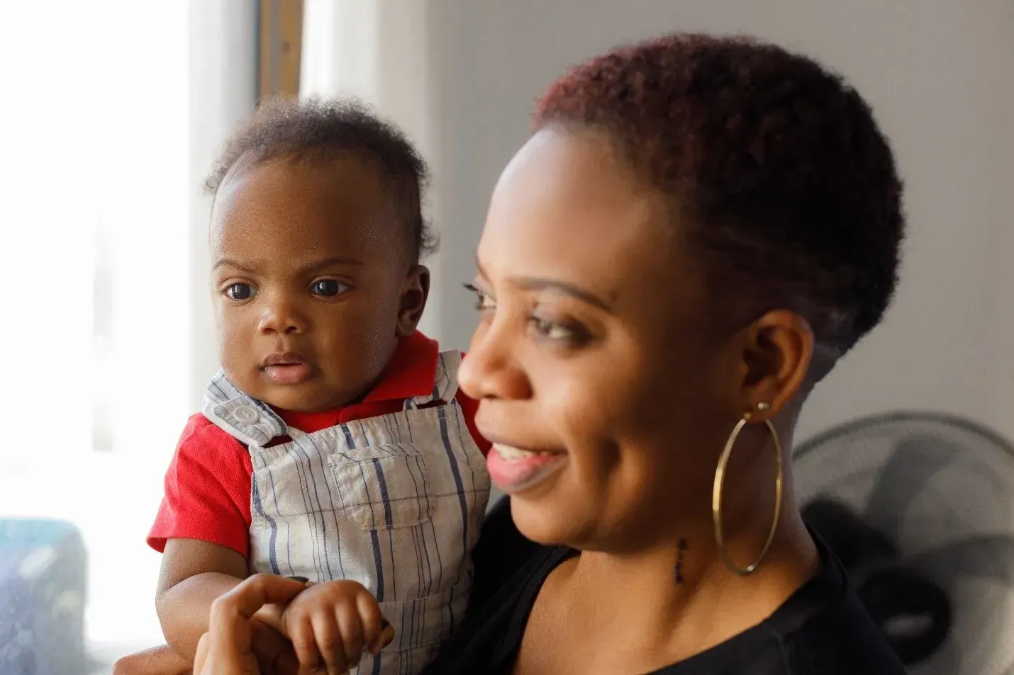 A woman is holding a baby in her arms and smiling. A woman is holding a baby in her arms and smiling.
