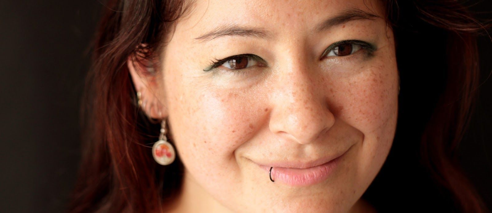 A close up of a woman 's face with a nose ring and earrings. A close up of a woman 's face with a nose ring and earrings.