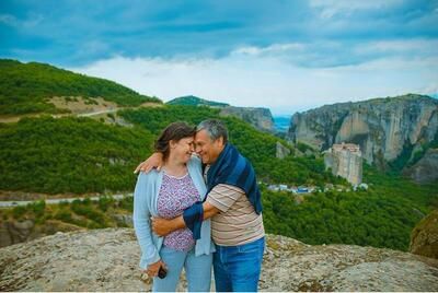 A man and a woman are standing on top of a mountain.