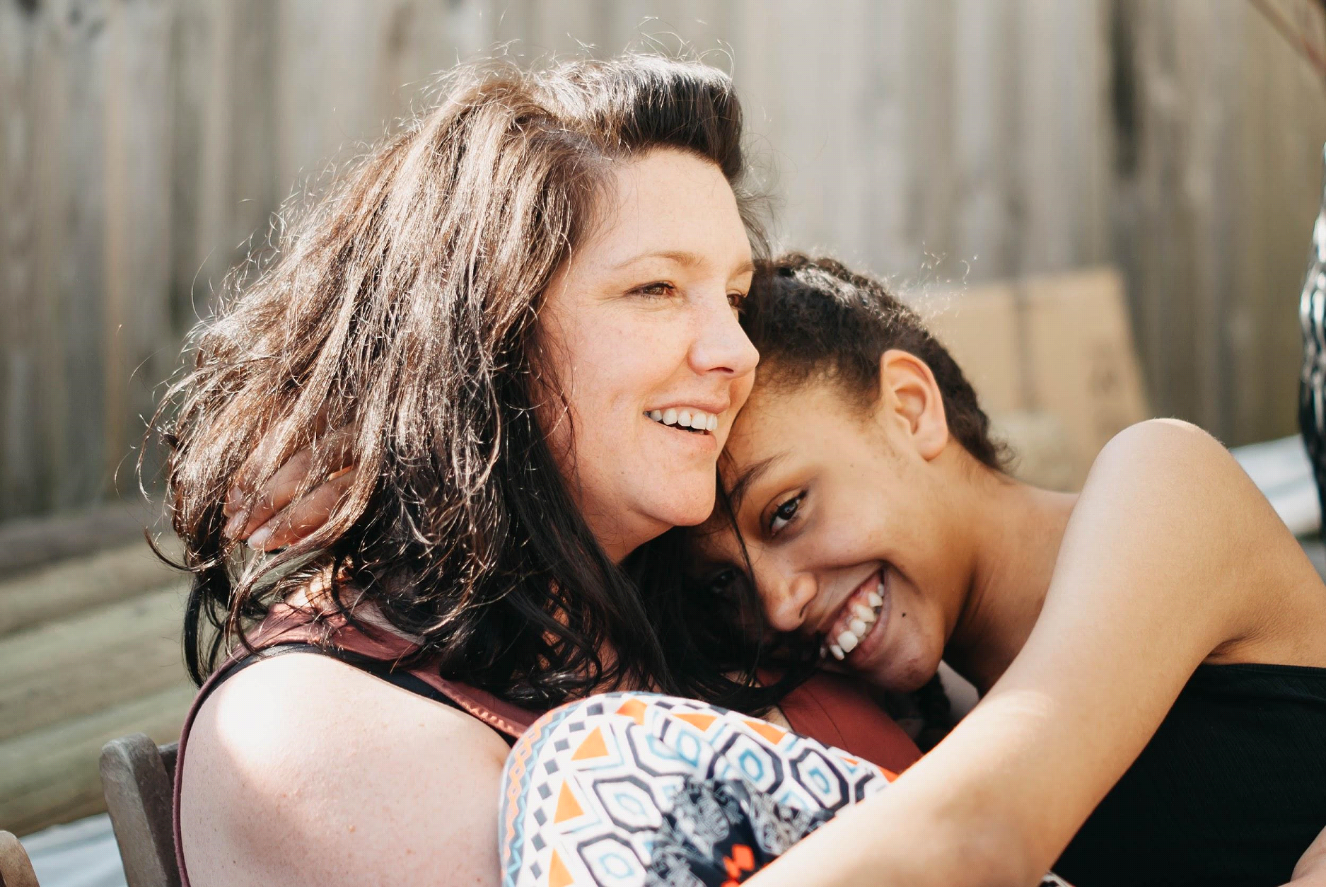 A woman and a young girl are hugging each other and smiling. A woman and a young girl are hugging each other and smiling.