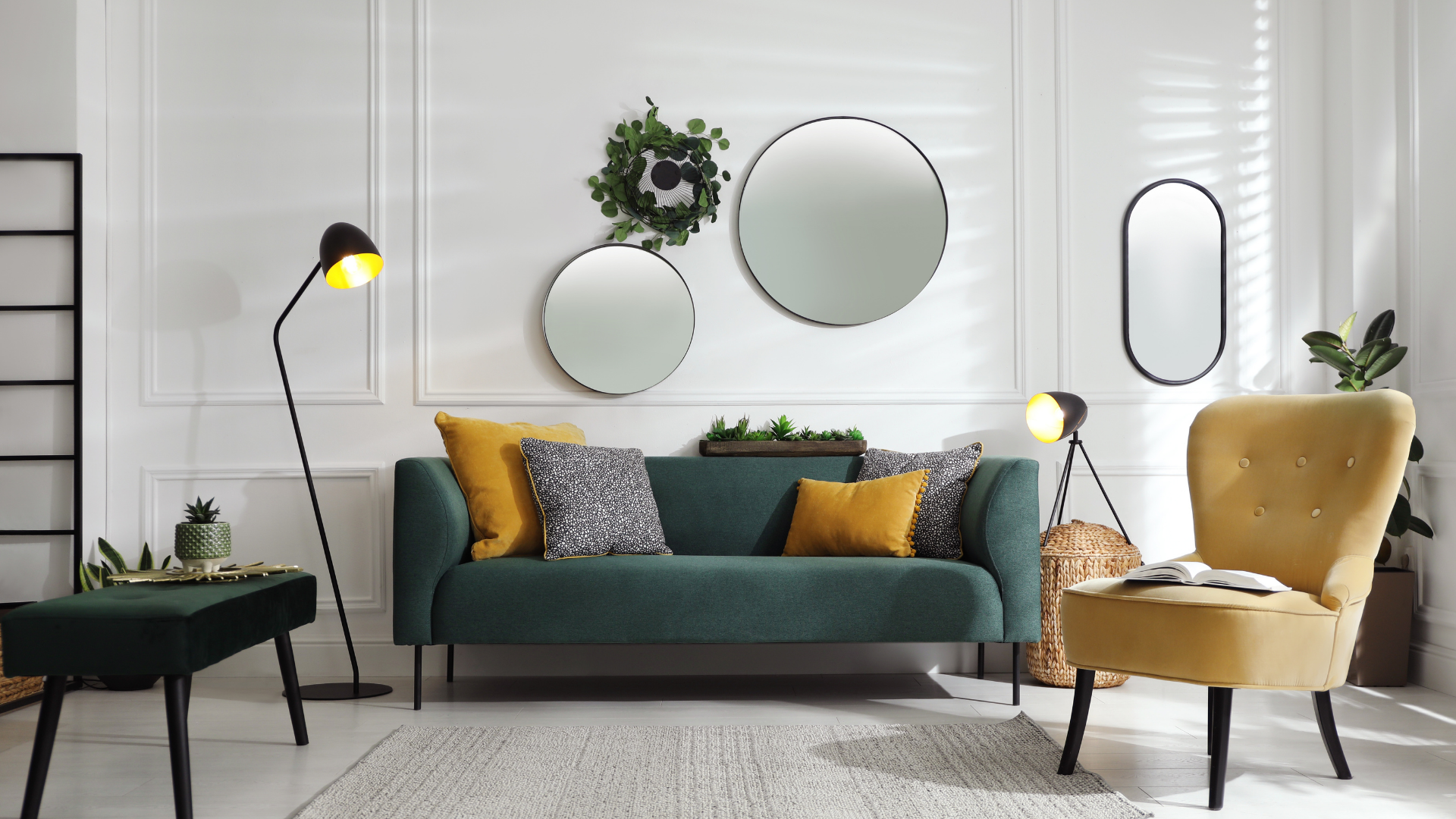 Living room with teal couch, gold chair, black lamps, and round mirrors on white wall.