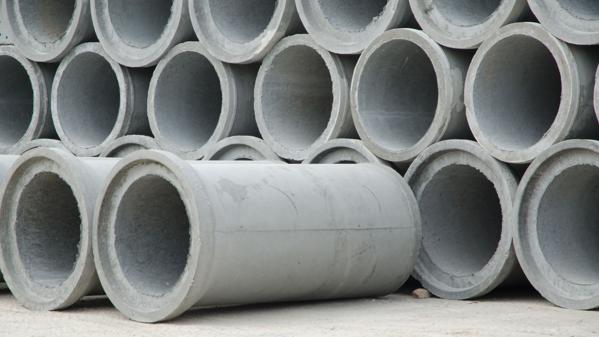 Concrete archway segments, outdoors. Large, gray, with bolt holes. Construction site in background.