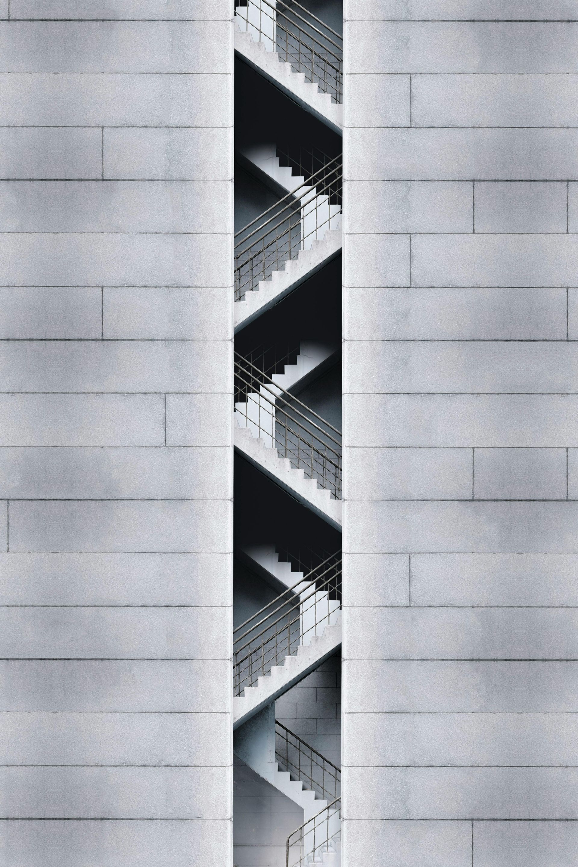 Exterior of a modern building with a vertical staircase visible through a long rectangular opening in the gray facade.