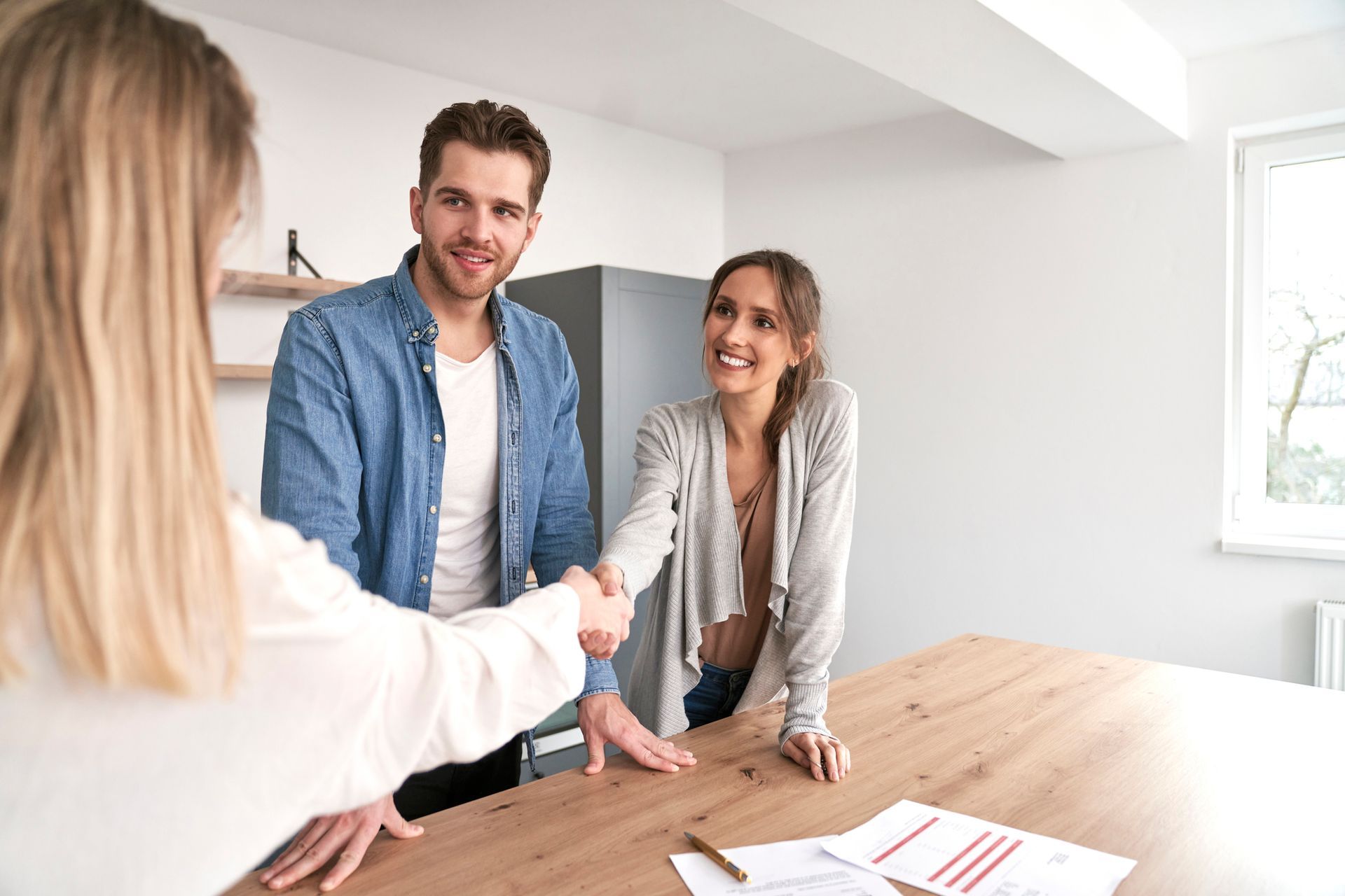 A man and a woman are shaking hands with a real estate agent.