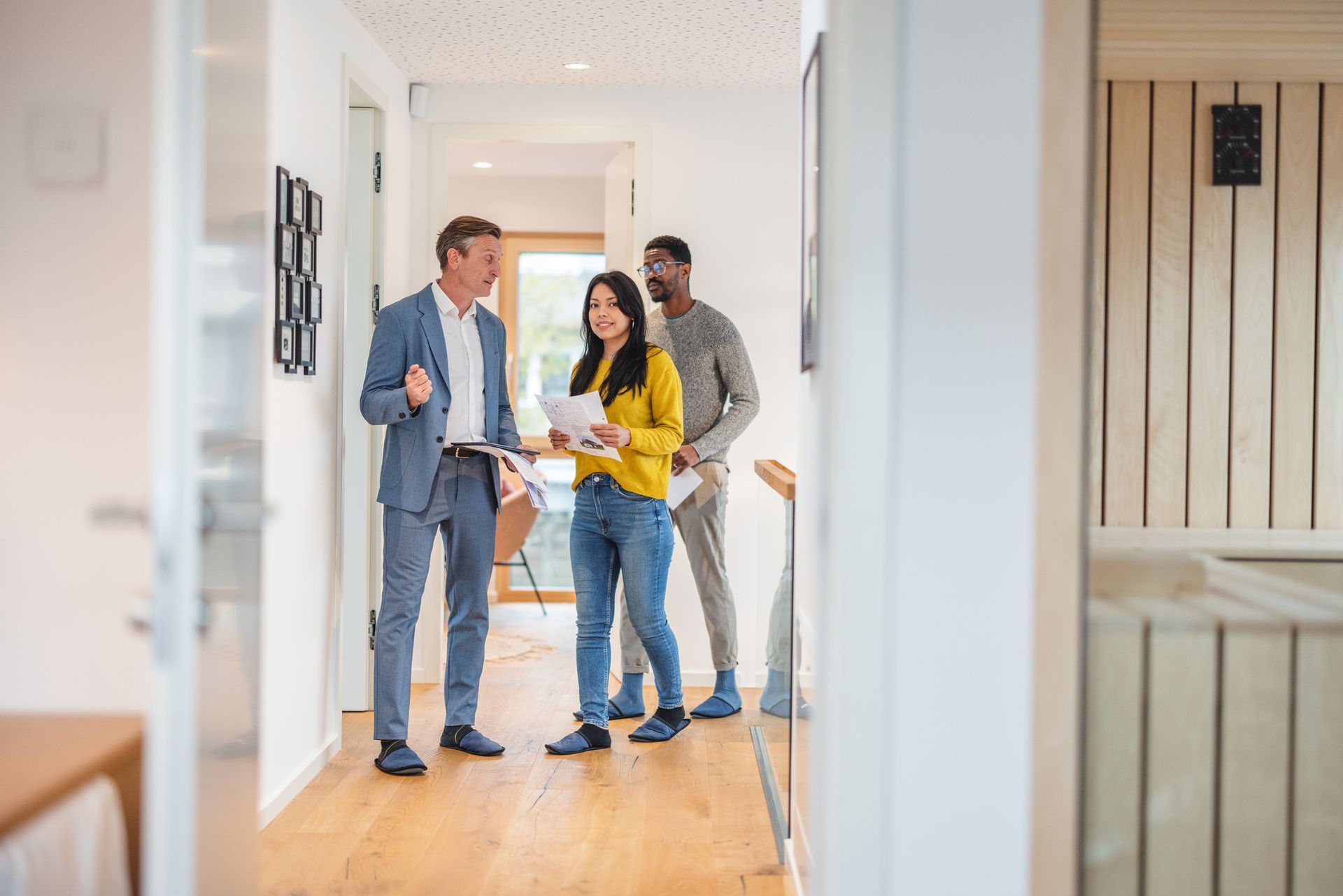 A group of people are standing in a hallway talking to each other.