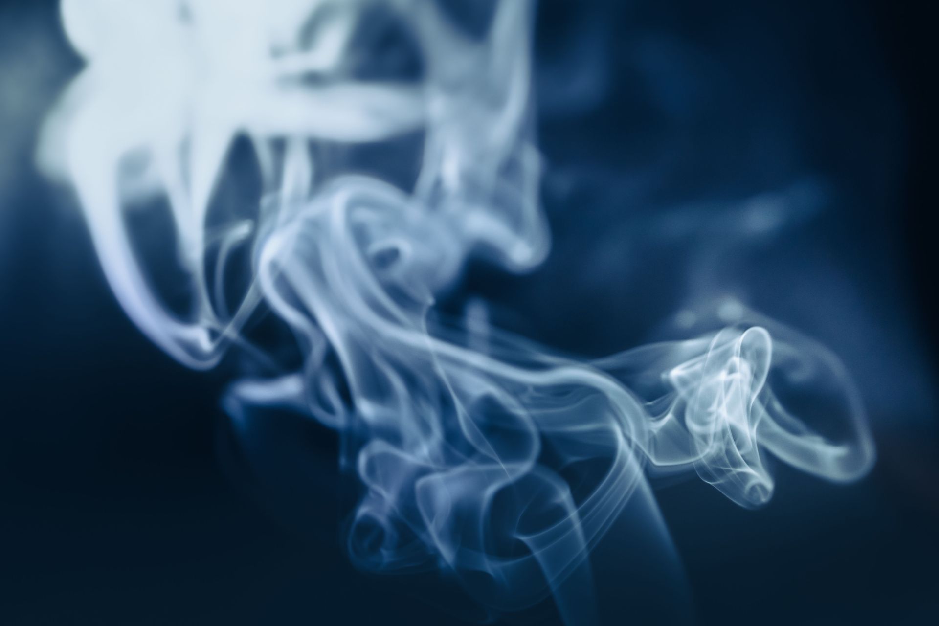 Volute di fumo bianco si arricciano contro uno sfondo blu scuro