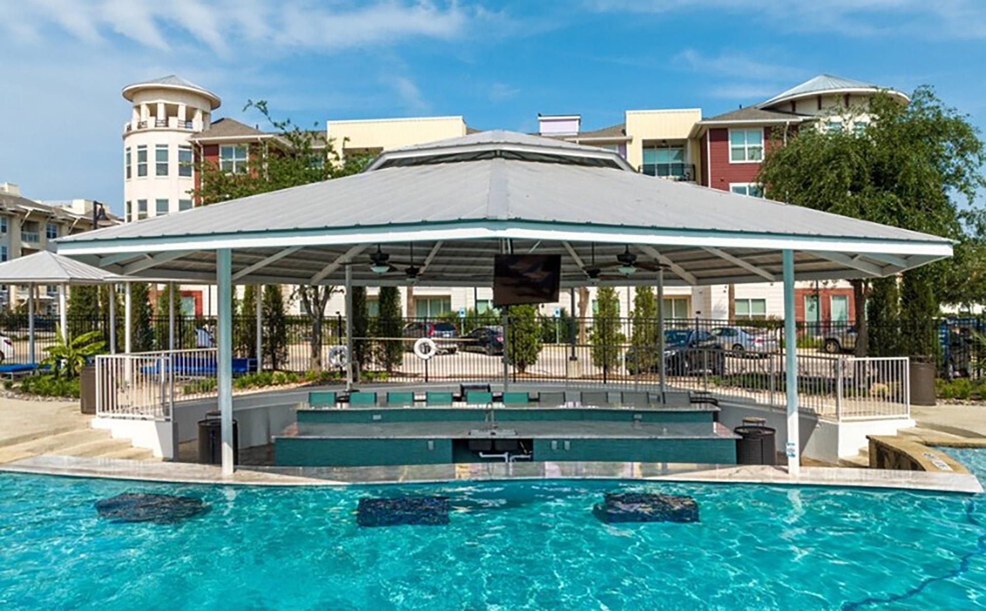 a swimming pool with a covered pavilion and a poolside jacuzzi