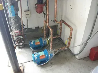 A person is fixing a water pump with a pressure gauge attached to it.
