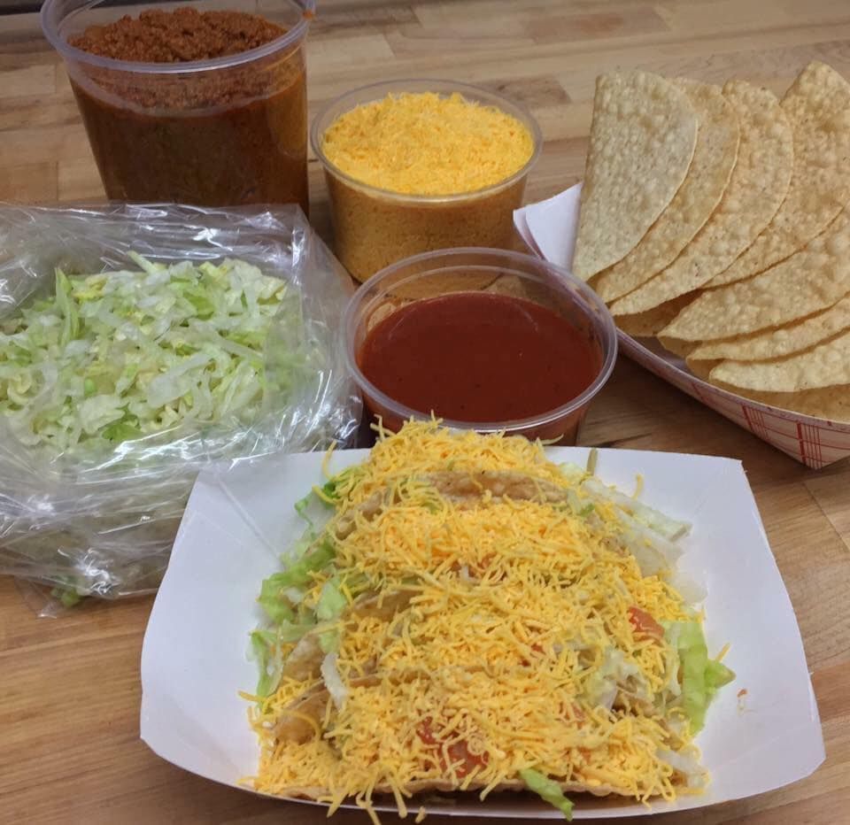 A taco with cheese lettuce and tortilla chips on a table