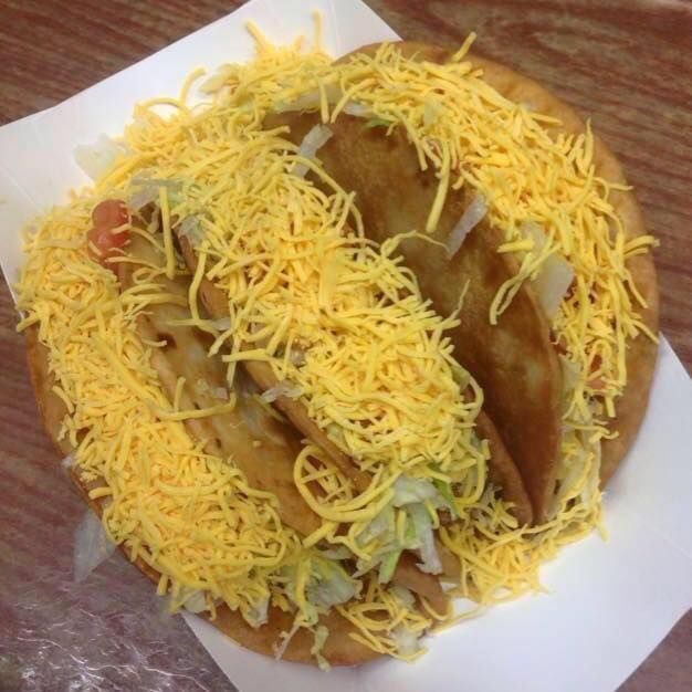 A close up of a taco with cheese and lettuce