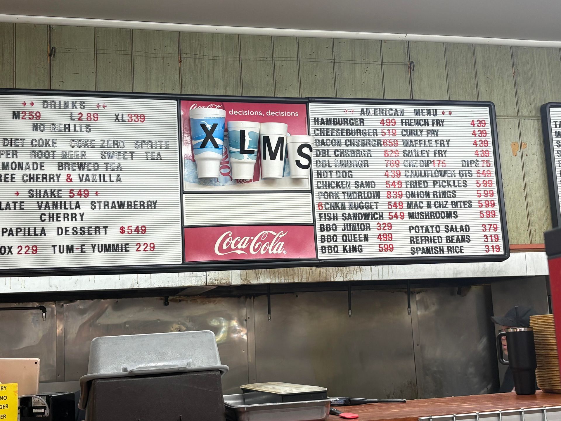 Menu board with drink sizes (XL, M, S) and food options, Coca-Cola logo.