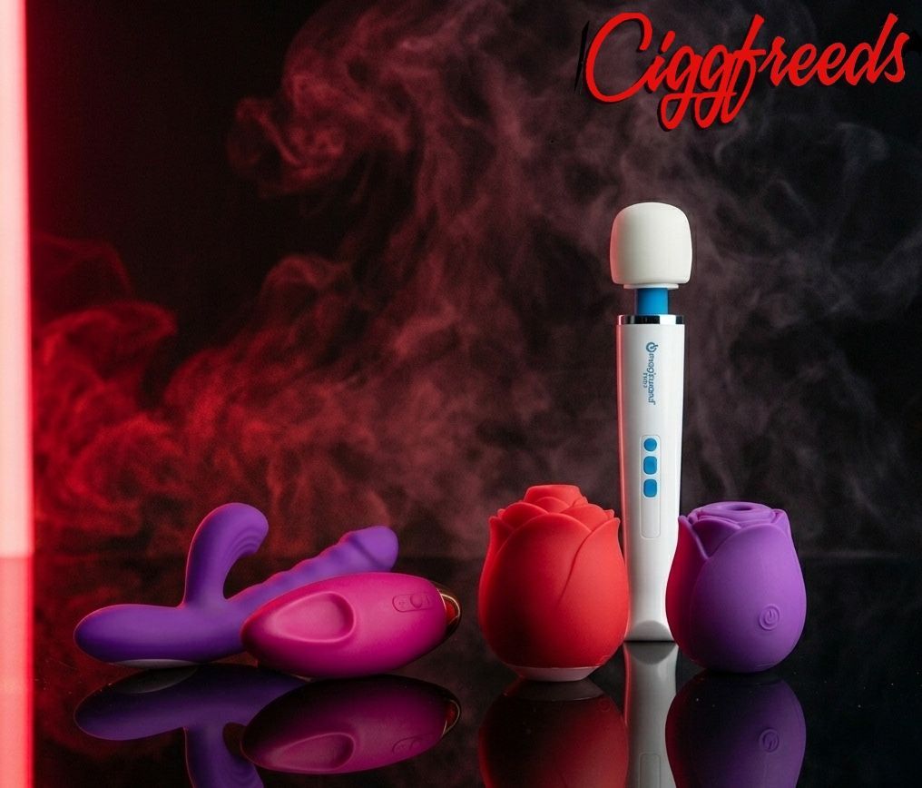 A collection of various vibrators in pink, orange, teal, and light blue arranged on a dark blue fabric background.