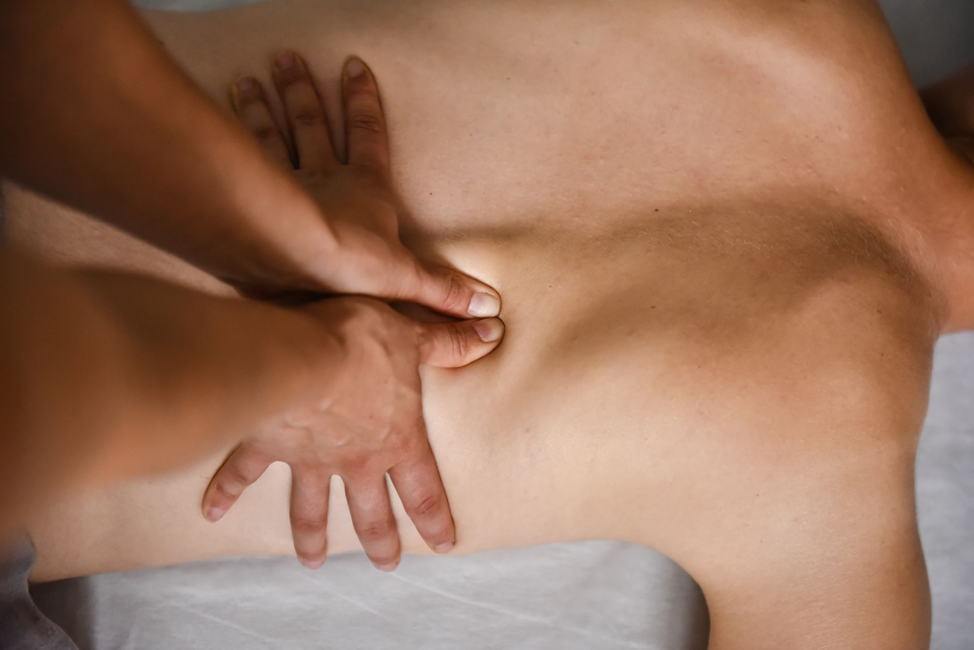 Hands pressing into a person’s back during a massage, close-up view