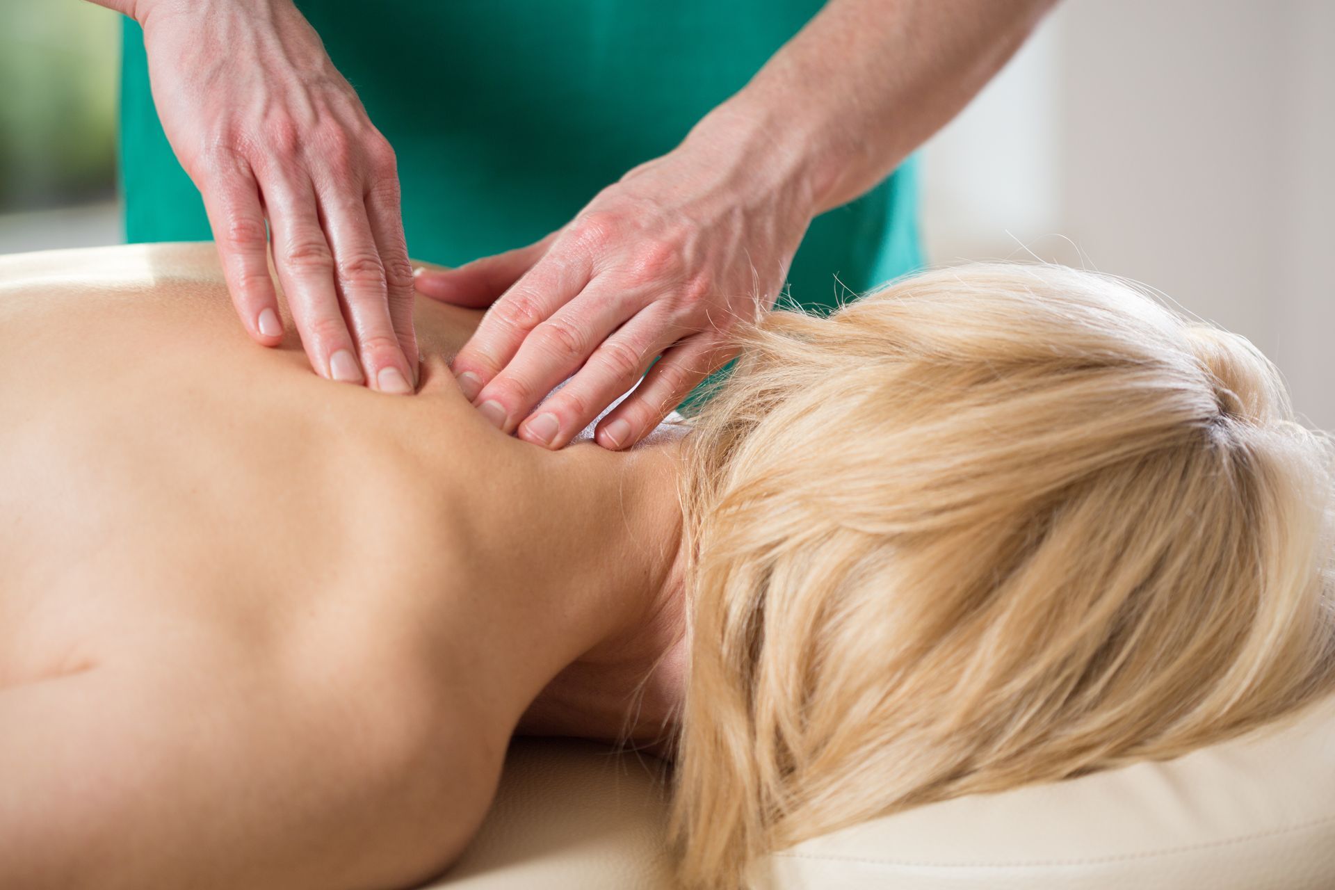 A woman is getting a massage from a man on a table.