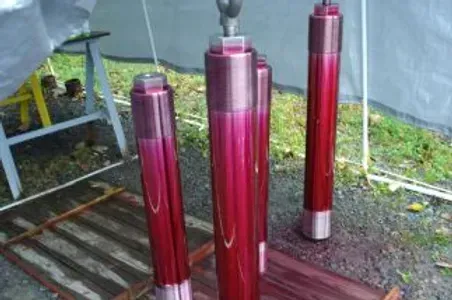 A bunch of red cylinders are sitting on top of a wooden pallet.