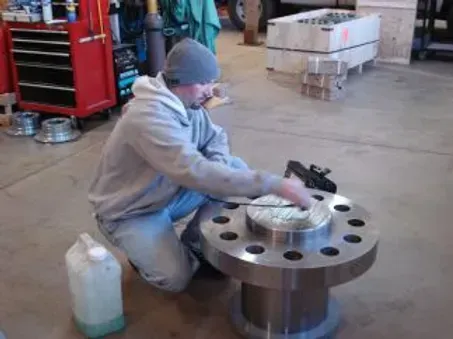 A man is kneeling down in front of a large metal object.