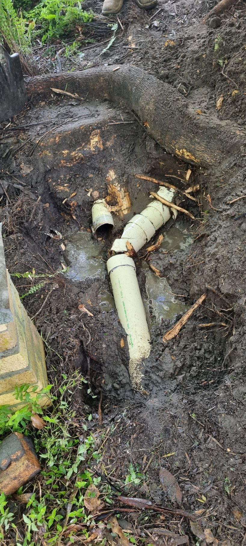 Broken White Pvc Pipes in Muddy Ground— Hills 2 Ocean Plumbing in Maclean, NSW