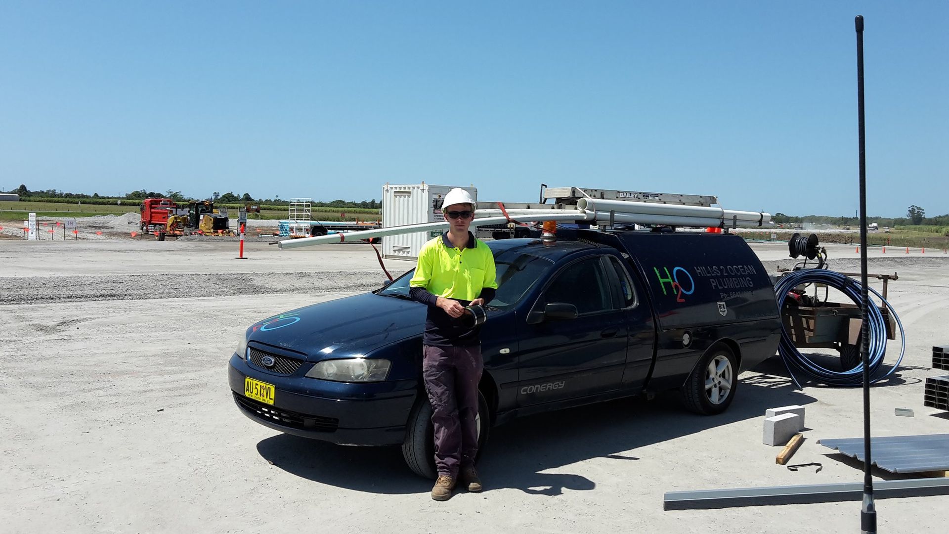 Person in Work Clothes Standing by a Dark Blue Utility Truck — Hills 2 Ocean Plumbing in Maclean, NSW