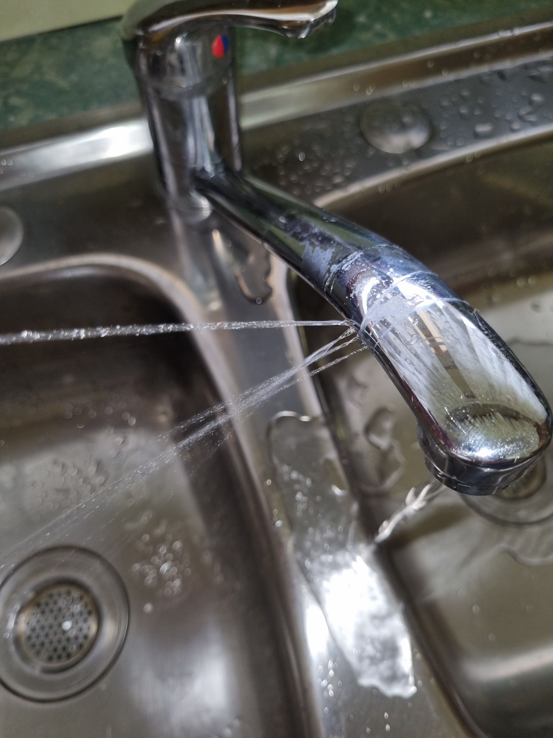 Stainless Steel Sink with A Chrome Faucet Spraying Water— Hills 2 Ocean Plumbing in Maclean, NSW