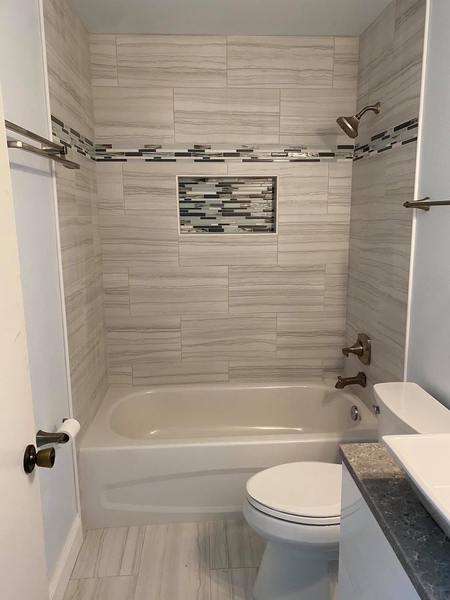 Small bathroom with white tub, toilet, and tiled shower walls. Small bathroom with white tub, toilet, and tiled shower walls.