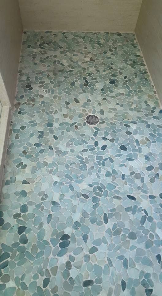 Small tiled shower floor with a drain in the center, bordered by beige walls.