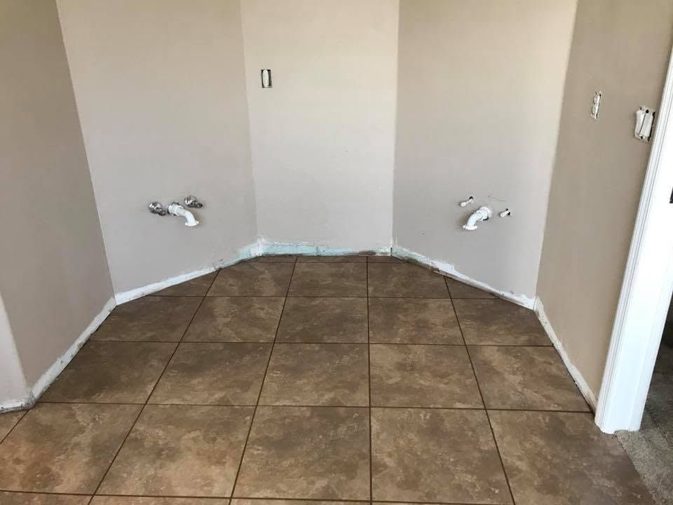 Empty laundry room with tan tile floor, beige walls, and plumbing hookups on both sides