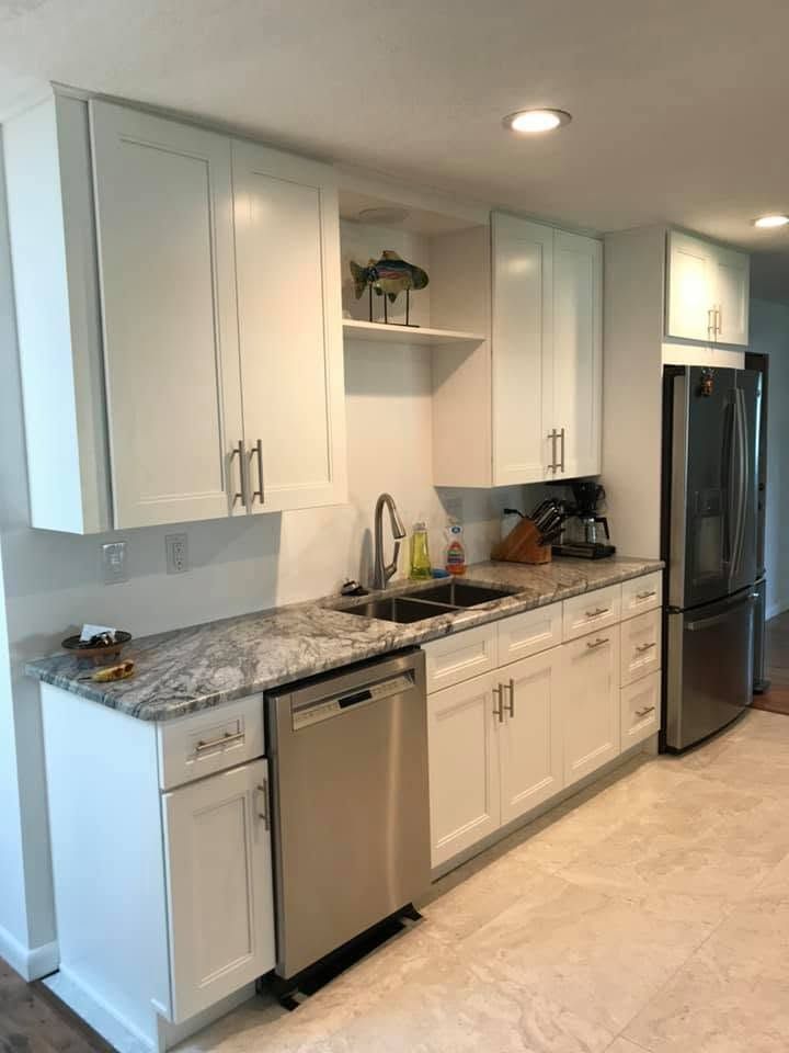 Modern white kitchen with granite countertops, stainless dishwasher, and black refrigerator Modern white kitchen with granite countertops, stainless dishwasher, and black refrigerator