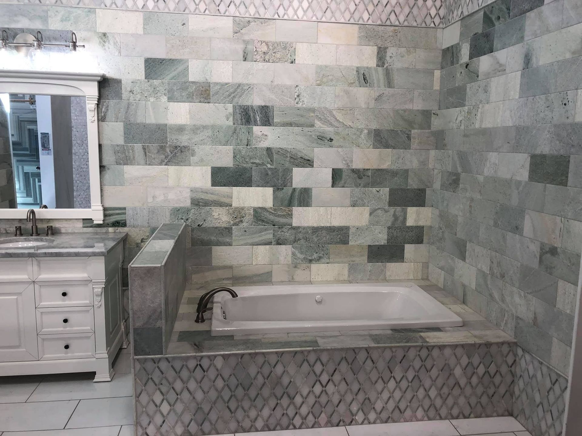 Bathroom with tiled walls, vanity mirror, and a bathtub with diamond-pattern tile surround.