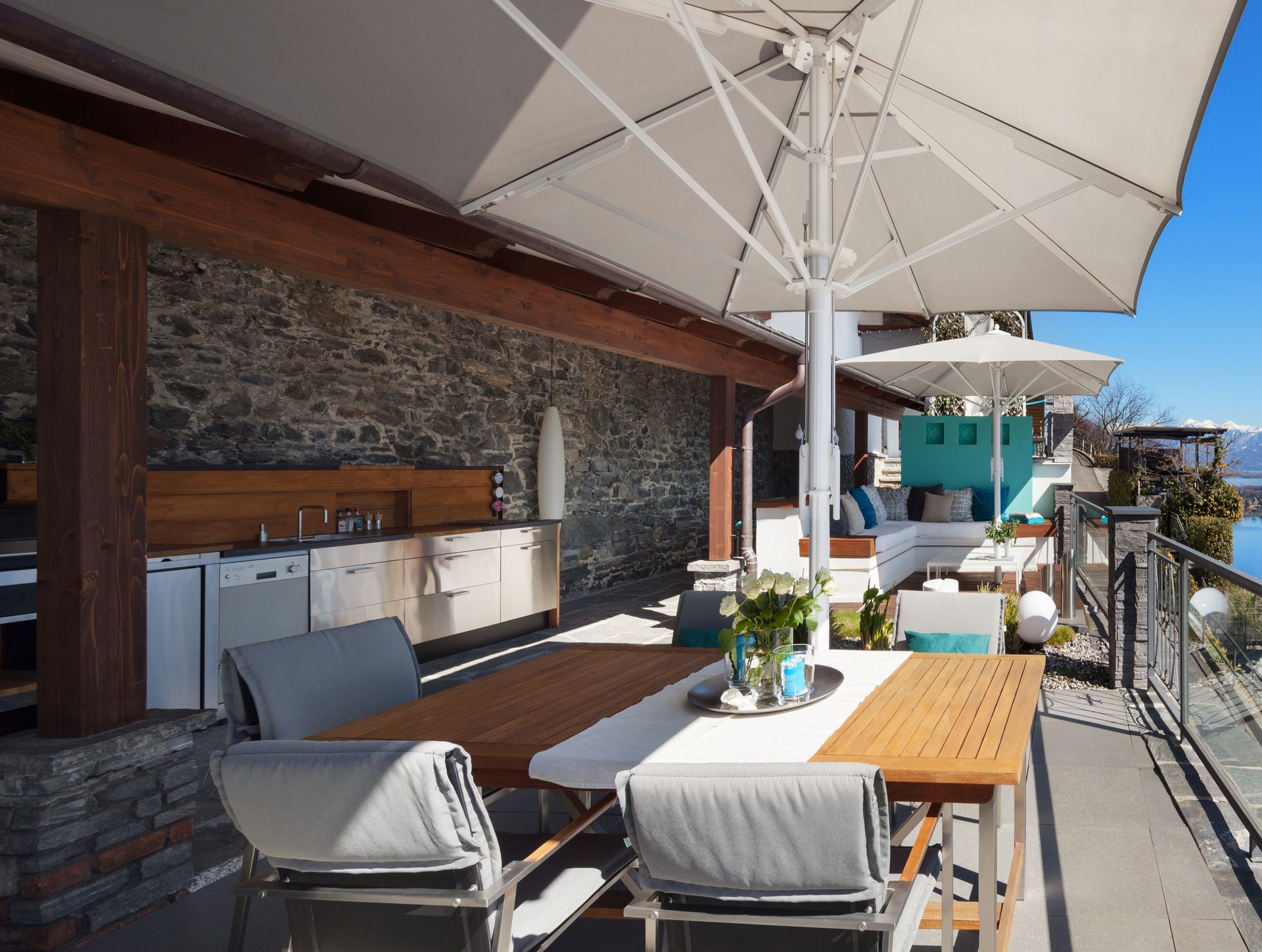 Outdoor patio dining area with white umbrellas, wooden table, gray seating, and ocean view Outdoor patio dining area with white umbrellas, wooden table, gray seating, and ocean view