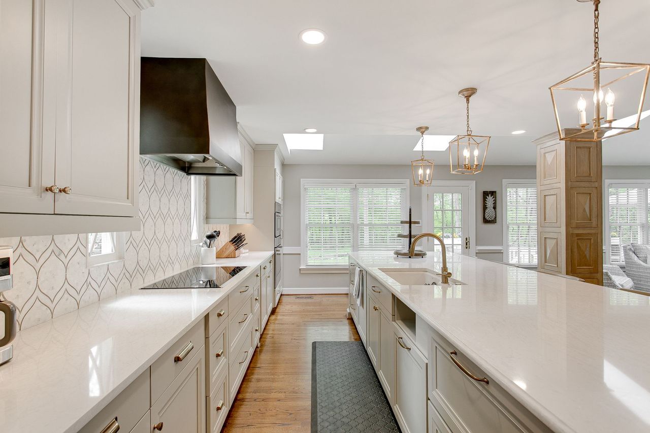 Bright modern kitchen with white cabinets, large island, stainless steel appliances, and pendant lights