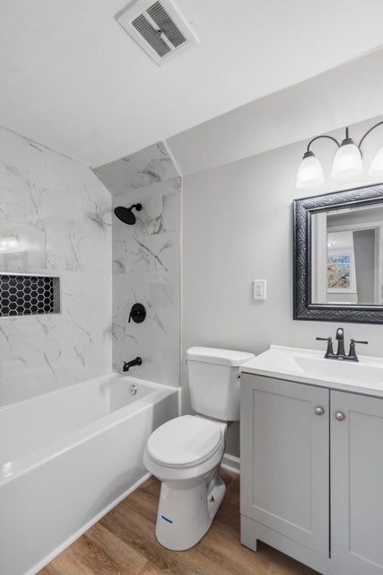 Modern bathroom with white and black accents; includes a tub, toilet, and vanity.