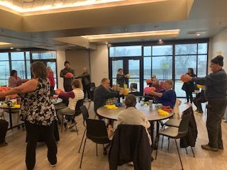 a group of people are sitting at tables in a room holding balloons