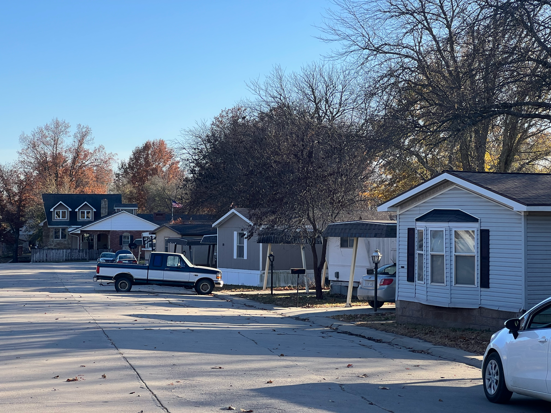 A white car is parked in front of a mobile home.
