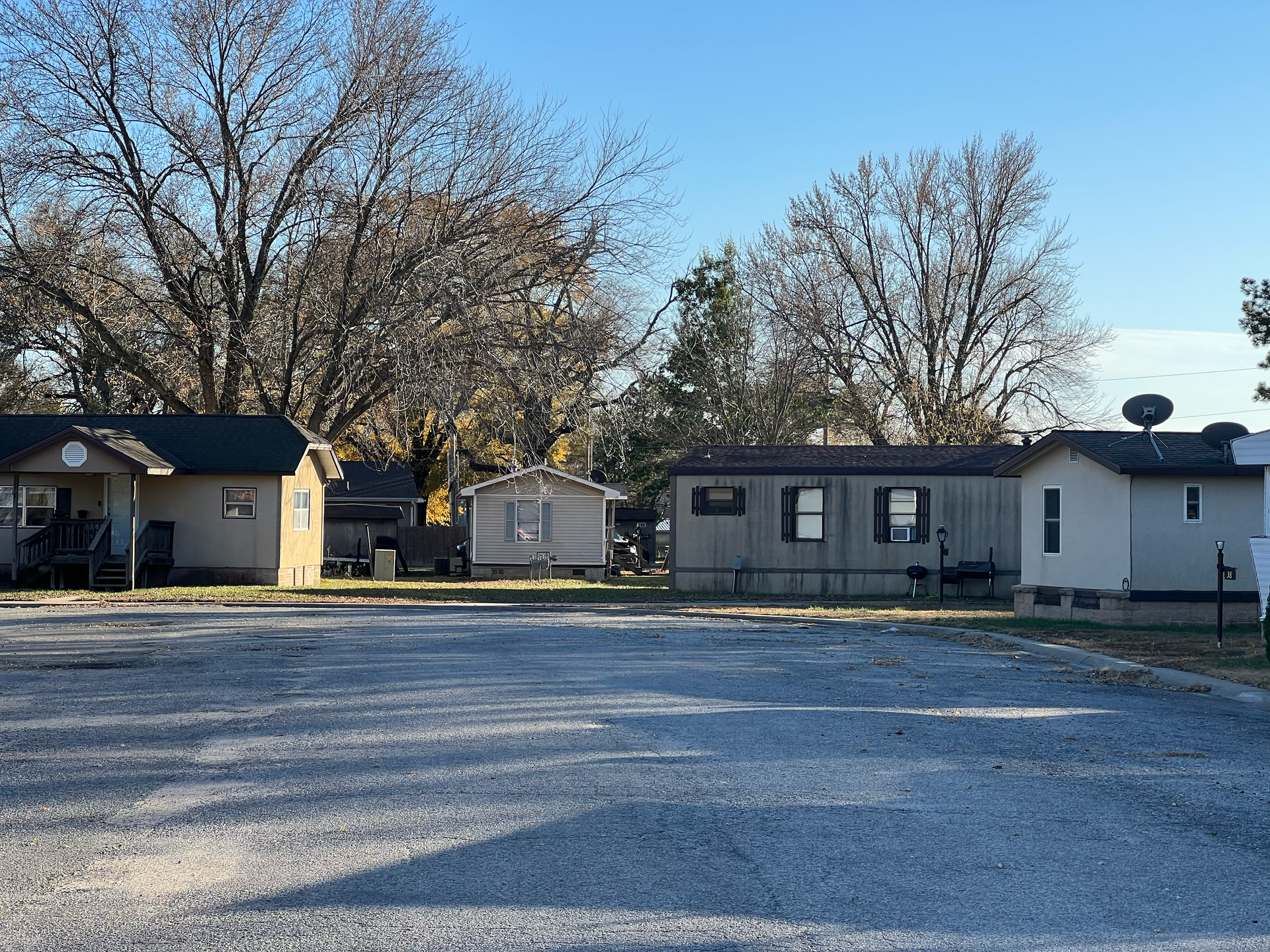 A group of mobile homes are parked in a gravel lot.