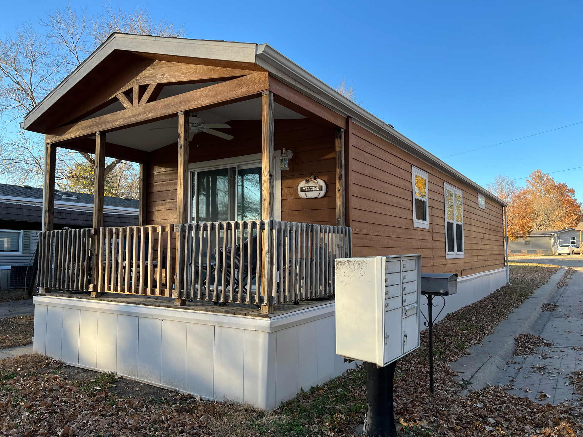 A mobile home with a porch and a mailbox in front of it.