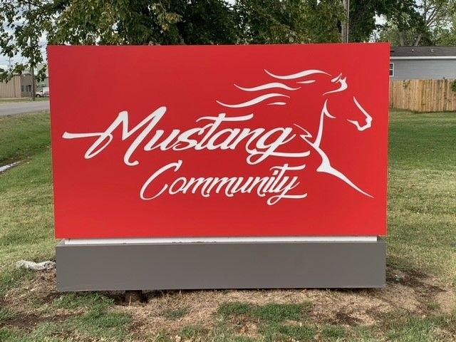A red mustang community sign with a white horse on it