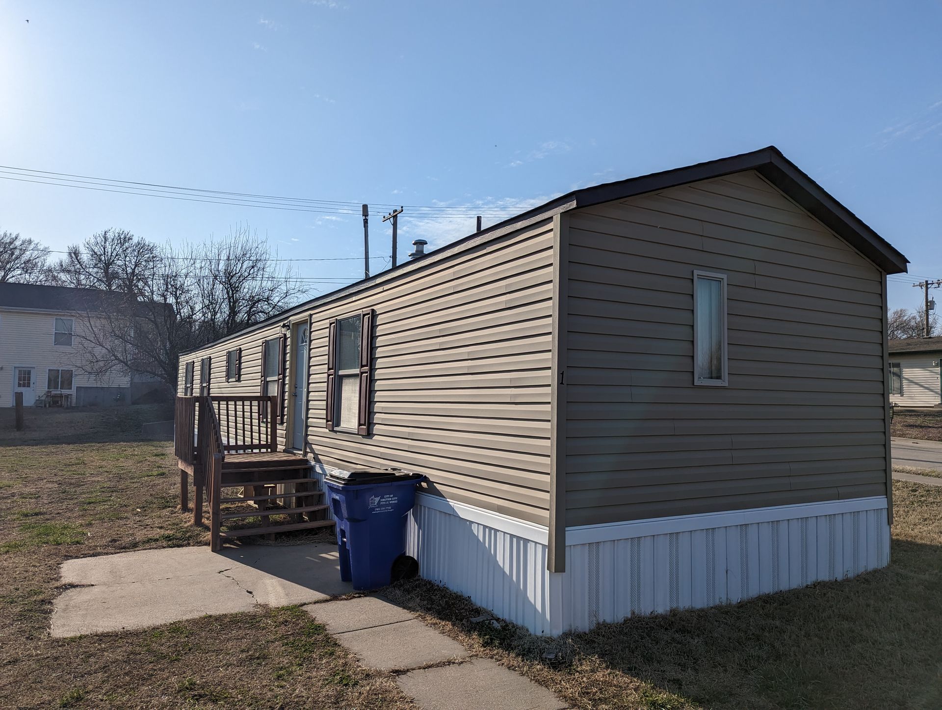 A mobile home with a blue trash can in front of it